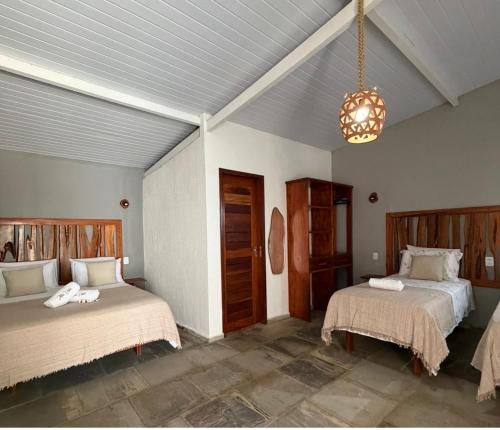a bedroom with two beds and a chandelier at Hotel Fazenda Alta Vista in Fortim