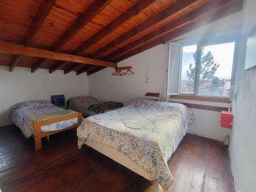 a bedroom with two beds and a large window at Cabañas Megustayacanto in Villa Yacanto