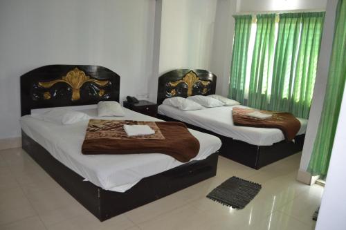 two beds in a room with green curtains at Hotel Shams Plaza in Cox's Bazar