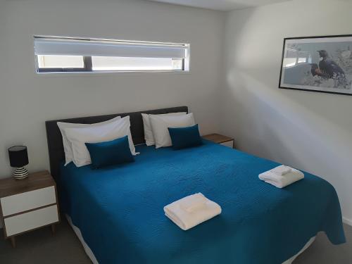 a bedroom with a blue bed with blue pillows at Harbourside Holiday Park in Whitianga