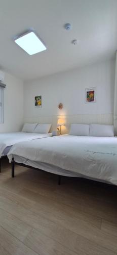 two beds in a white room with a large bed at 1&2stayㅡH in Tongdaegu-yŏk