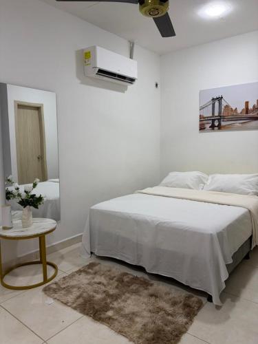 ein weißes Schlafzimmer mit einem Bett und einem Tisch in der Unterkunft Oasis Olmos in Cereté