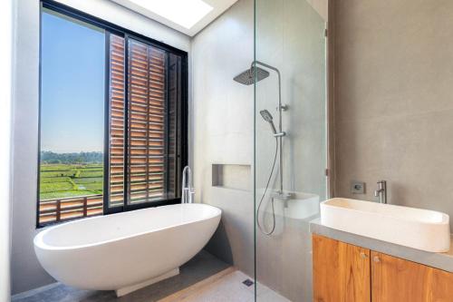 a bathroom with a tub and a sink and a window at Duality Villas in Ubud