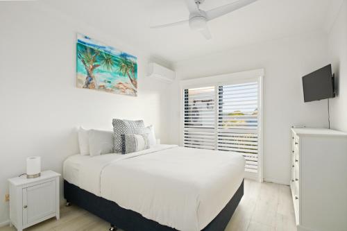 a white bedroom with a bed and a tv at Riverfront 2BR Apt with Views, Balcony & Parking in Maroochydore