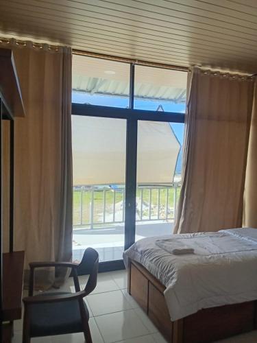 a bedroom with a bed and a chair and a window at Blue Rose Resort & Dive Center in Pattimura Airport