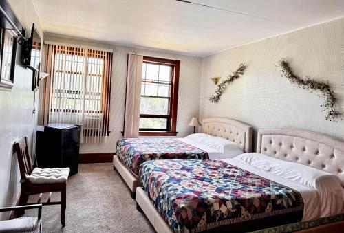 a bedroom with two beds and a chair and windows at Rock Castle Resort in Lake George