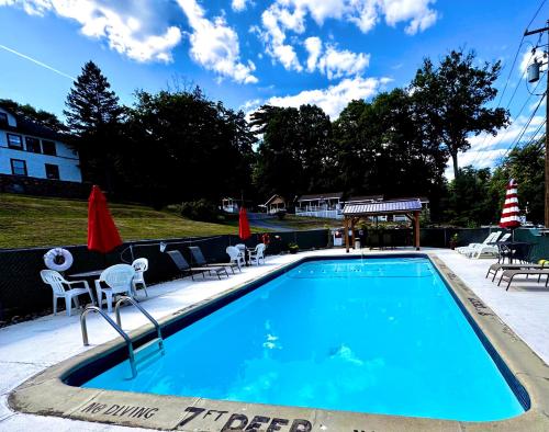 a swimming pool with chairs and a table and umbrellas at Rock Castle Resort in Lake George