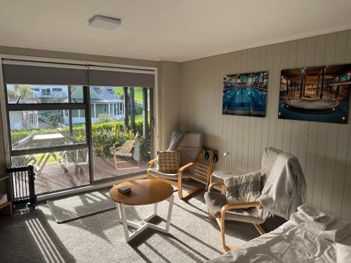 a living room with chairs and a table and a balcony at The Pacific Room, Tapeka Point in Russell
