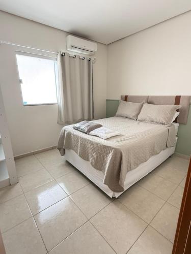 a white bedroom with a bed with a window at Casa parque 18 in Araguaína