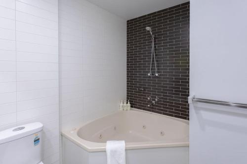 a white bathroom with a tub and a toilet at Bay View - Green Vista in Lorne