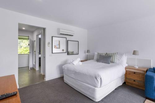a white bedroom with a white bed and a desk at Bay View - Green Vista in Lorne
