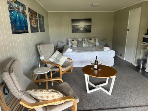 a bedroom with a bed and a table and chairs at The Pacific Room, Tapeka Point in Russell