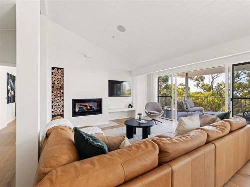 a living room with a brown couch and a fireplace at Eagle Heights - Elevated Oasis with Pool & Sea Views in Dunsborough