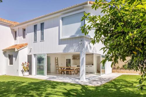 a white house with a patio and a table at Torretta by the Bay in Dunsborough