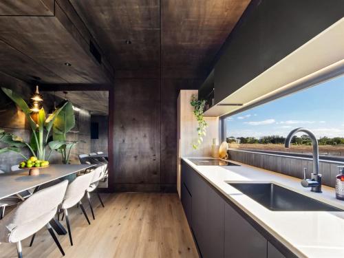 a kitchen with a sink and a counter with chairs at Samphire Chalet Tuart - Luxury Amidst Nature in Geographe