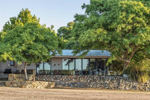 a house with a stone wall and two trees at Petra Olive 1 in Yallingup