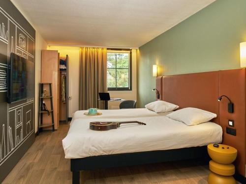 a hotel room with two beds and a desk at Ibis Sarlat Centre in Sarlat-la-Canéda