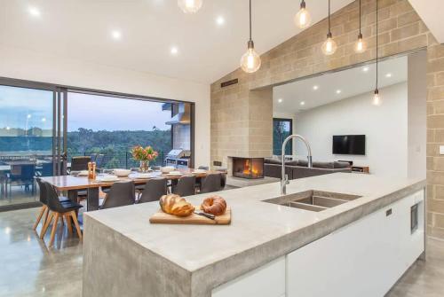 a kitchen and dining room with a table and a fireplace at Lake View - Contemporary Comforts meets Nature in Quindalup