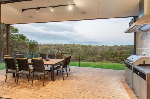 a patio with a table and chairs and a large window at Lake View - Contemporary Comforts meets Nature in Quindalup