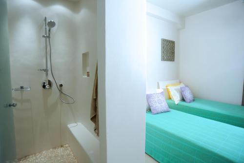 a bathroom with a shower and a bed with blue sheets at Lidia Villa in Panormos Mykonos