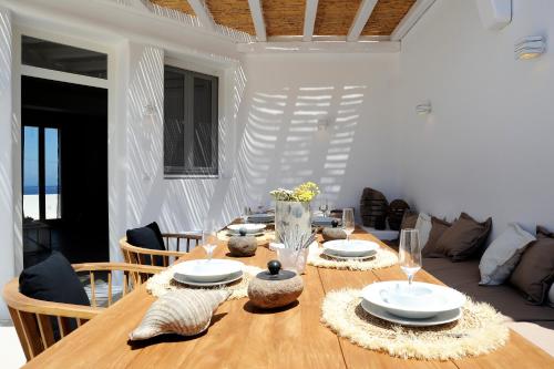 a dining room with a wooden table and a couch at Lidia Villa in Panormos Mykonos