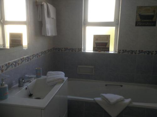 a bathroom with a tub and a sink and two windows at Votre appartement a Portimao in Portimão