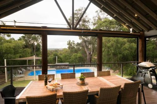 a dining area with a wooden table and chairs at Sky View - Elevated Estate with Resort-Style Pool in Yallingup