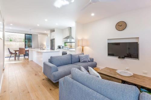 a living room with two blue couches and a kitchen at Yallingup Lagoon Beach House in Yallingup