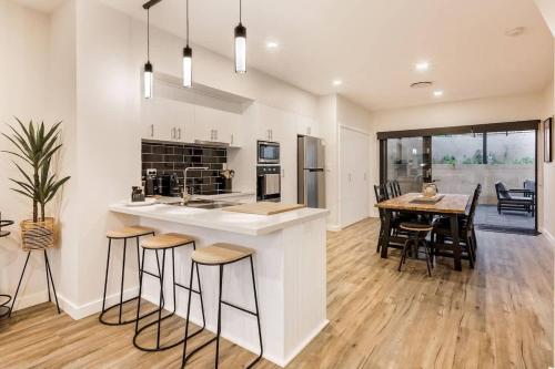 a kitchen and dining room with a counter and stools at Rabbits Break - Beachside Bliss Steps from Yallingup in Yallingup