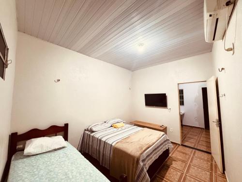 a bedroom with two beds and a tv in it at Pousada e Hostel das Rosas in Barreirinhas