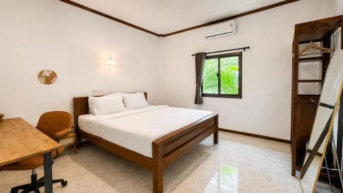 a bedroom with a bed and a desk and a window at Zen Harmony Pool Villa in Ko Phangan
