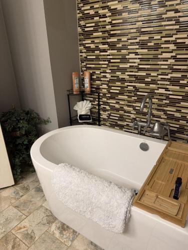 a white bath tub in a bathroom with a tile wall at The Audobon Escape in Aiken