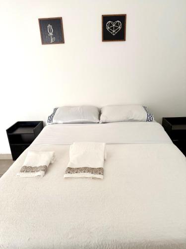 a white bed with two white towels on it at Lumar Apart Boituva Diária 24H in Boituva