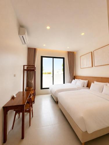 a hotel room with two beds and a table at Tim Kanya Pranburi in Pran Buri