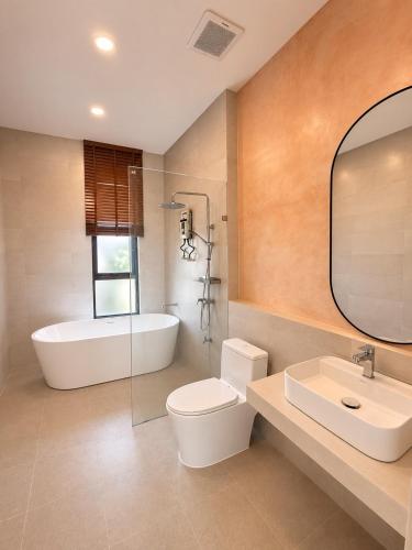 a bathroom with a tub and a toilet and a sink at Tim Kanya Pranburi in Pran Buri