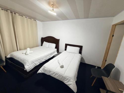 two beds in a room with a desk and a chair at Zenora Suites in San José