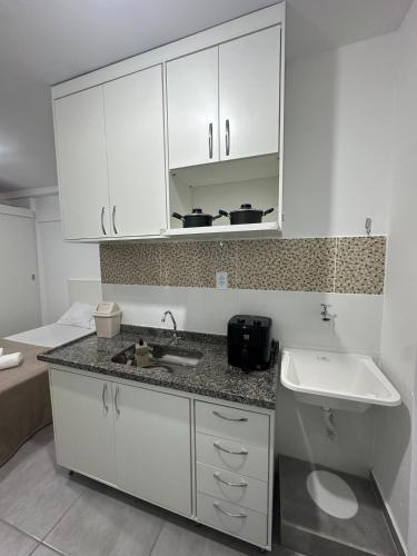 a kitchen with white cabinets and a sink at Studio Blanc - Espaço e conforto com uma vista incrivel in Barbacena