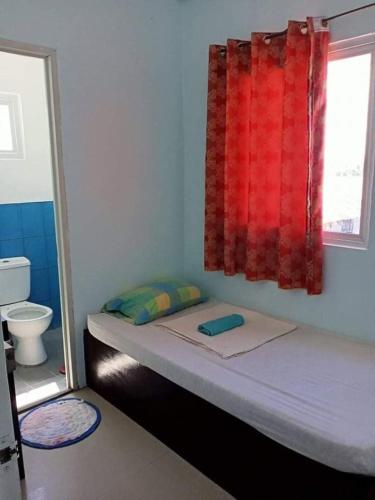 a small bedroom with a bed with a red window at Walk Inn Dipolog City by RedDoorz in Dipolog