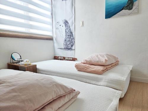 two beds sitting in a room with a window at Como Green House in Busan