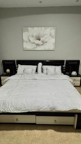 a large bed with a white flower painting above it at بيّت الضيافة in Al Baha