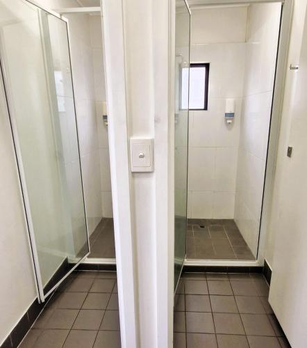 a walk in shower in a bathroom with glass doors at The Grand Hotel Cairns in Cairns