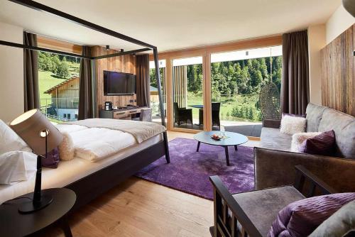 Alpin Life Resort Lürzerhof في أونتيرتاورين: غرفة نوم بسرير كبير وغرفة معيشة