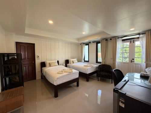 a hotel room with two beds and a table and chairs at Loy Manee House in Phra Nakhon Si Ayutthaya