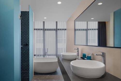 two sinks in a bathroom with two mirrors at Quest Vibe Dewi Sri Bali in Legian