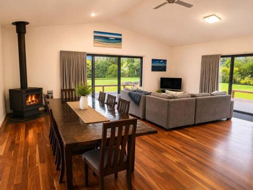 a living room with a couch and a table and a fireplace at Bawley Backyard Haven - family retreat near beach in Bawley Point
