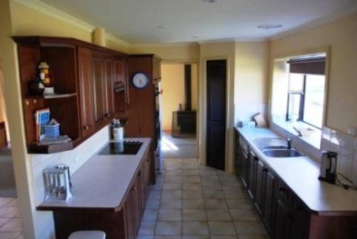 a large kitchen with wooden cabinets and a counter top at Seaside Haven in Port Welshpool