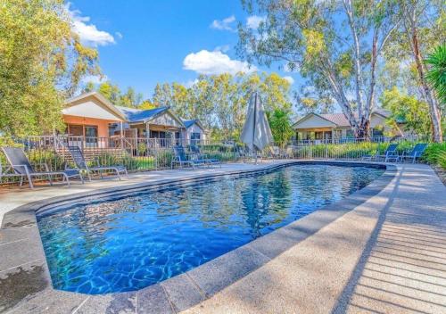 a pool with chairs and umbrellas in front of a house at #4 Riverspa in Moama