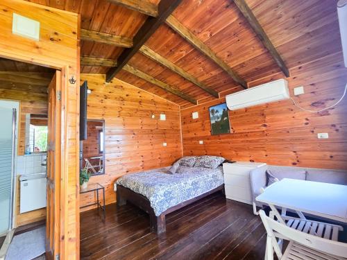 a bedroom in a log cabin with a bed and a table at Assaf's place - המקום של אסף in Aẖihud