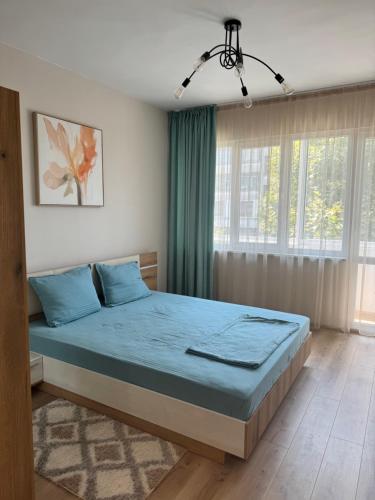 a bedroom with a bed with blue sheets and a window at Апартамент Кари in Yambol