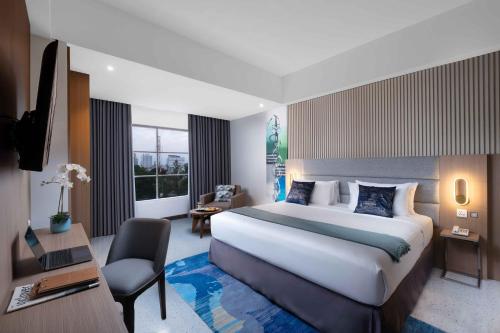 a hotel room with a large bed and a desk at Oakwood Merdeka Bandung in Bandung